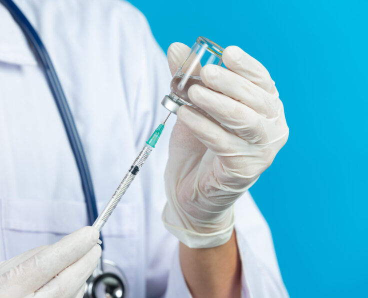 close up picture of doctor's hands holding hypodermic syringe